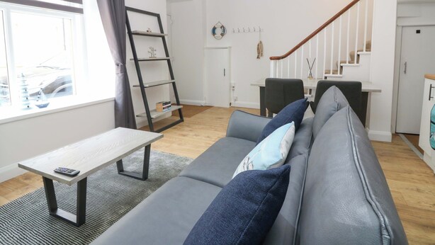 A modern living room with a grey sofa, a small table, and a ladder shelf. - 3 Caroline Place (Fraserburgh)