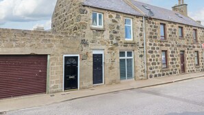 A stone building with multiple doors and windows, a garage door, and a chimney. - 3 Caroline Place (Fraserburgh)