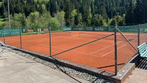 A tennis court with a net, surrounded by a fence, and a bench. - Room '6' with Mountain View, Shared Terrace and Wi-Fi (Hopfgarten in Tirol)