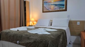 Ett hotellrum med en säng, ett nattduksbord, en lampa och en tavla på väggen.