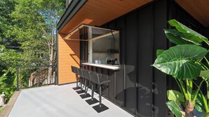 An outdoor bar area with a wooden ceiling, black walls, and a concrete floor. - Modern Muskoka River Retreat (Bracebridge)