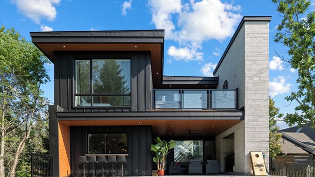 A modern two-story house with a flat roof, large windows, and a balcony. - Modern Muskoka River Retreat (Bracebridge)