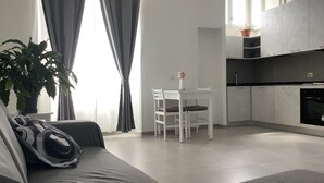 Una sala de estar moderna con un sofá, una mesa de comedor con sillas, y una cocina con armarios y estufa.