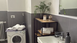 Un baño moderno con lavadora integrada, un lavamanos y un espejo.