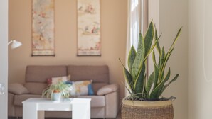 A living room with a sofa, a coffee table, and a potted plant.