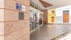A building entrance with a stone facade, a blue plaque, and a glass door.