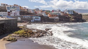 A coastal town with colorful buildings, rocky shoreline, and waves crashing onto the beach.