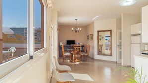 A modern living room with a dining area, a TV, and a kitchen.