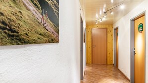 Un passadís amb una porta de fusta, un senyal penjat a la paret i un paviment de rajoles.