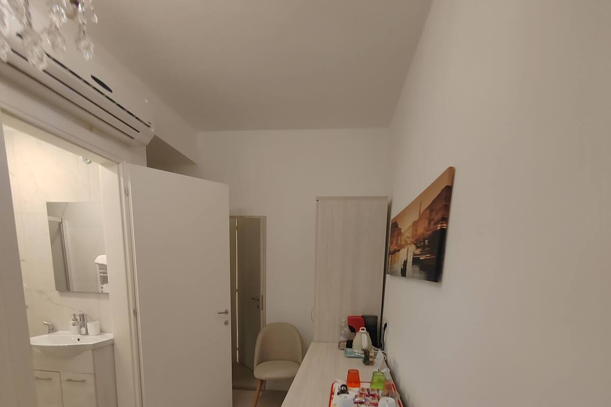 A modern, well-lit room with a kitchenette, a dining area, and a chair.