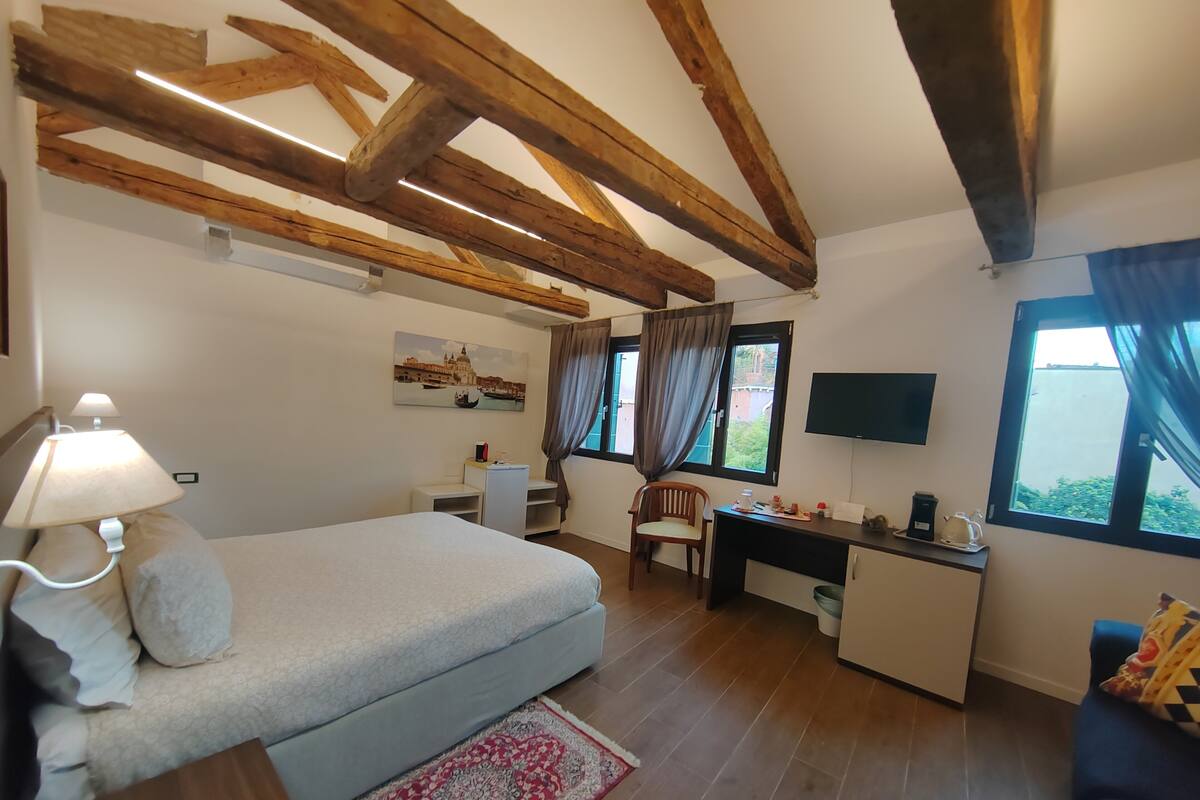 A bedroom with a bed, desk, chair, and a TV.