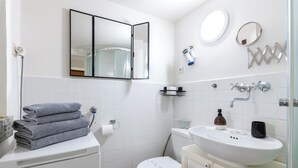 A modern bathroom with a white toilet, a sink with a mirror, and a towel rack. - New Town Riverside Apartment (Hlavní město Praha)