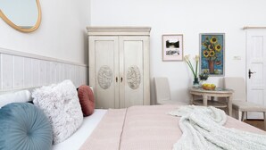 A bedroom with a bed, pillows, a wardrobe, a small table with a vase of flowers, and a framed picture on the wall. - New Town Riverside Apartment (Hlavní město Praha)
