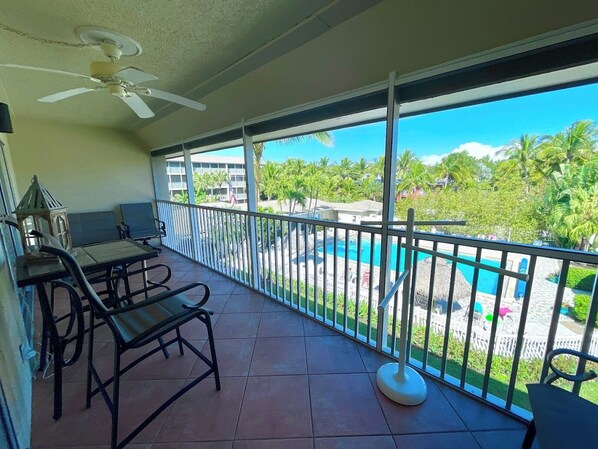 A balcony with a pool view, a ceiling fan, and outdoor furniture. - Sanibel Siesta on the Beach (Sanibel)