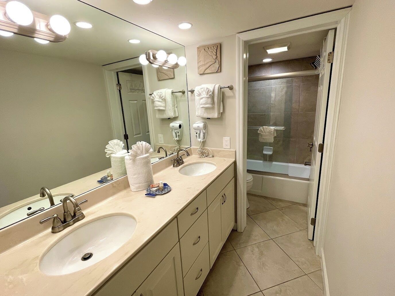 A modern bathroom with two sinks, a large mirror, and a shower.