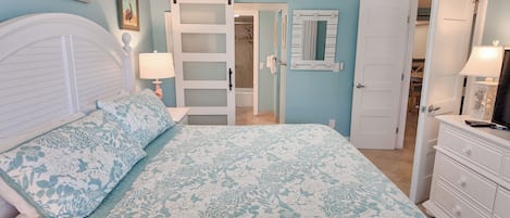 A bedroom with a bed, a dresser, a mirror, and a sliding door to a bathroom.