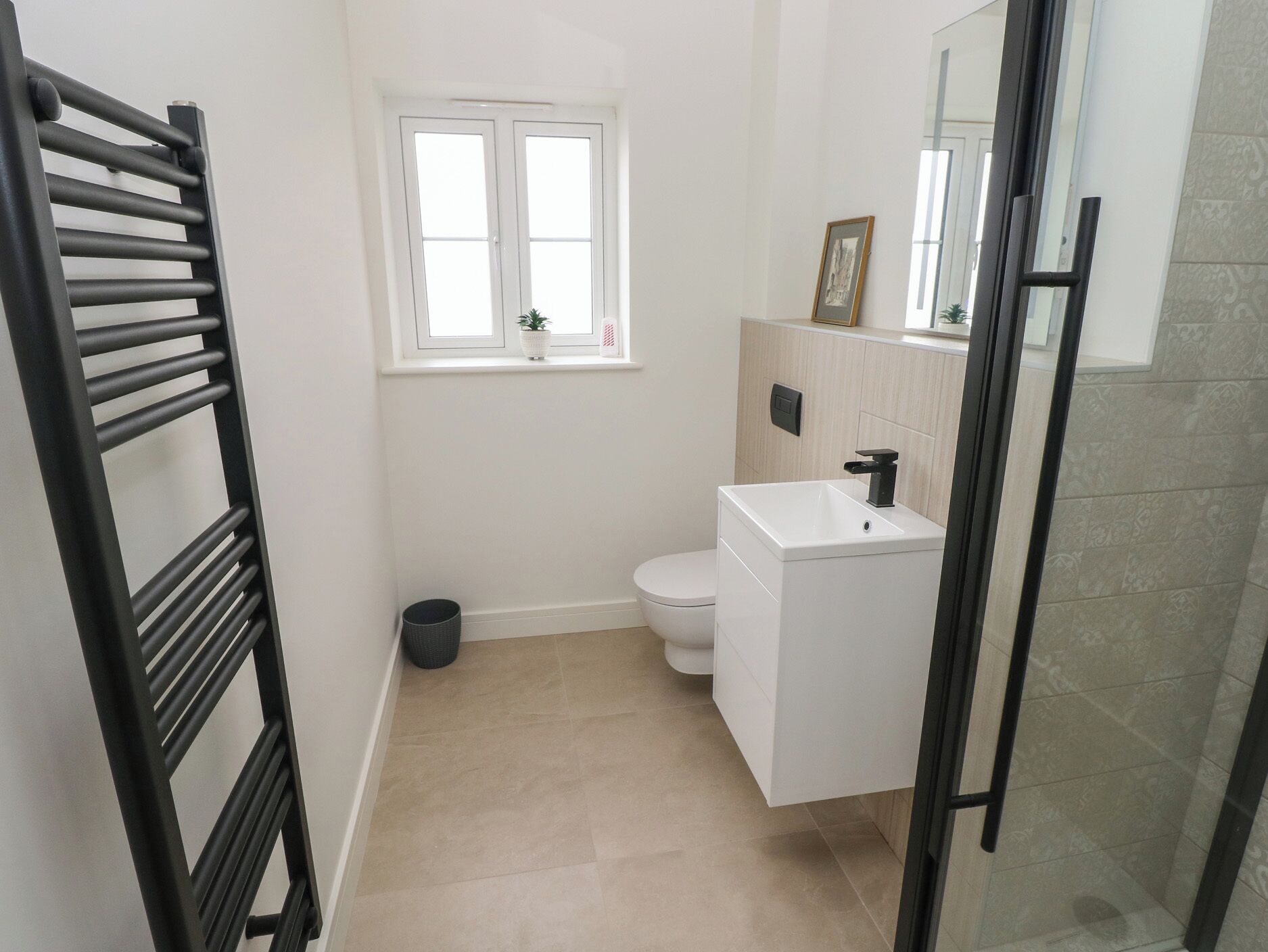 A modern bathroom with a white sink, toilet, and a window above the toilet.