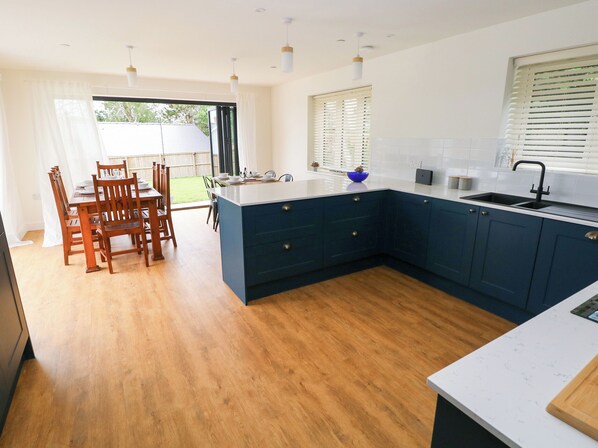 A modern kitchen with a large island, dark blue cabinets, and a white countertop.