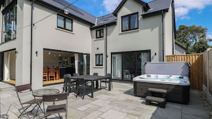 A modern house with a patio, a hot tub, and a dining area.