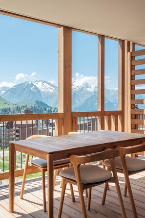 A wooden deck with a table and chairs, overlooking a mountain range. - Sola Modern ski-in ski-out Alpe d'Huez (Huez)
