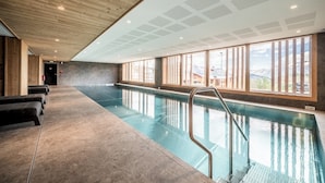 A swimming pool with a wooden ceiling and large windows.
