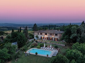 Une villa dotée d’une piscine, entourée d’une végétation luxuriante et avec des collines en arrière-plan.
