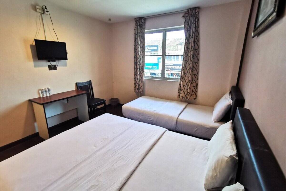 A hotel room with two beds, a desk, a television, and a window with curtains.