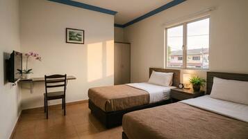 A hotel room with two beds, a desk with a chair, a TV, and a window with a view of buildings.