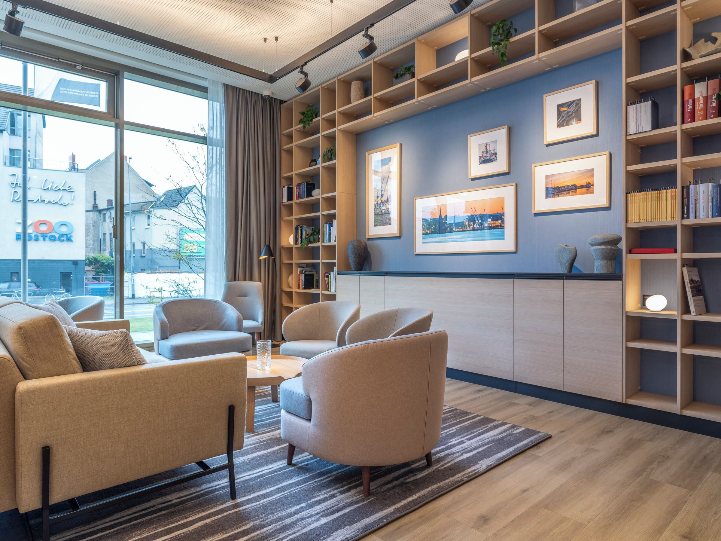 A modern living room with a sofa set, a coffee table, and a bookshelf with framed pictures.