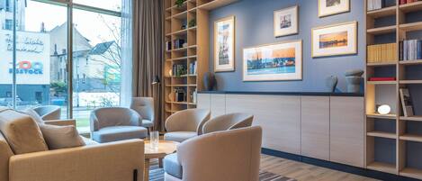 A modern living room with a sofa set, a coffee table, and a bookshelf with framed pictures.