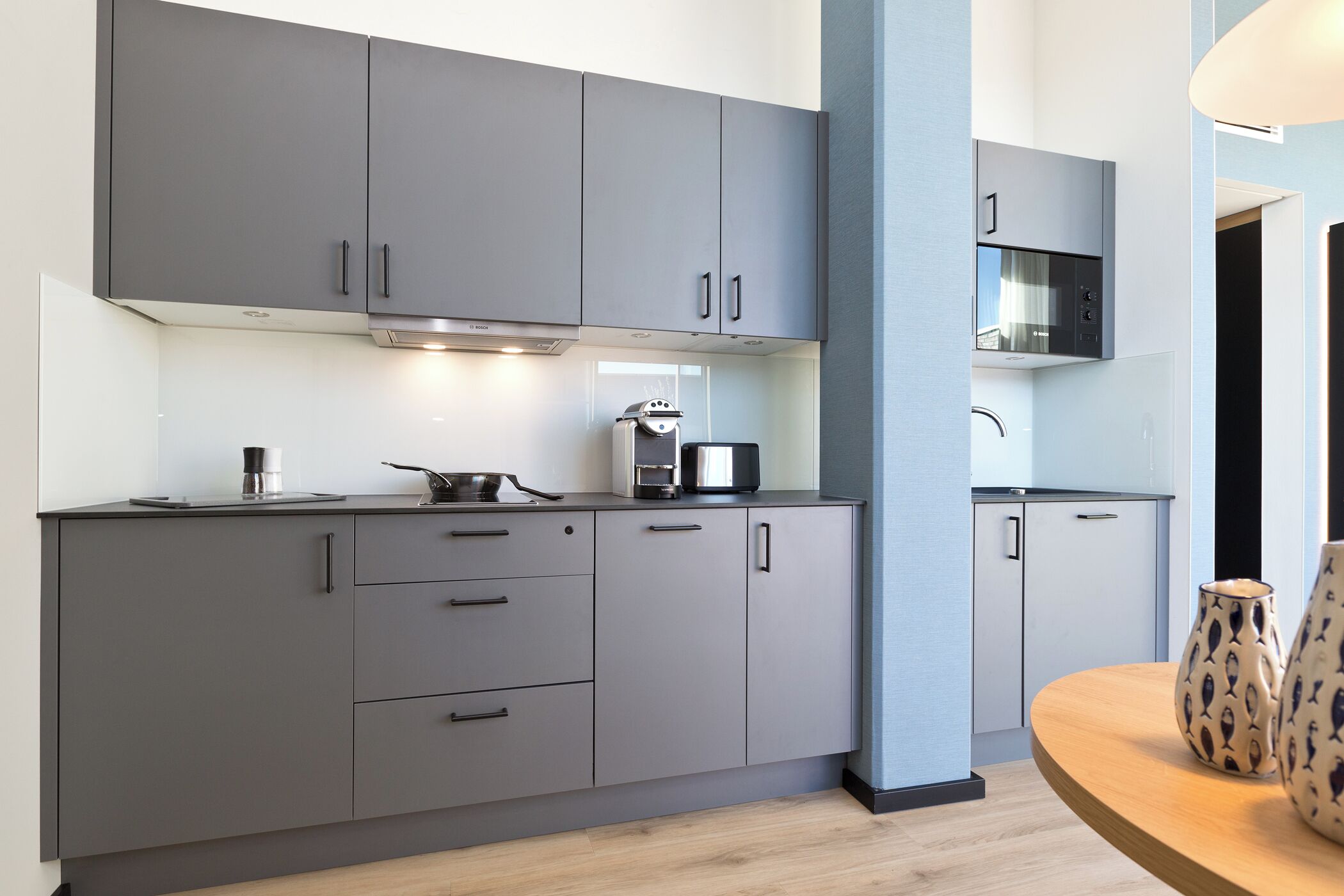 Una cocina moderna con armarios grises, una cafetera y un microondas.