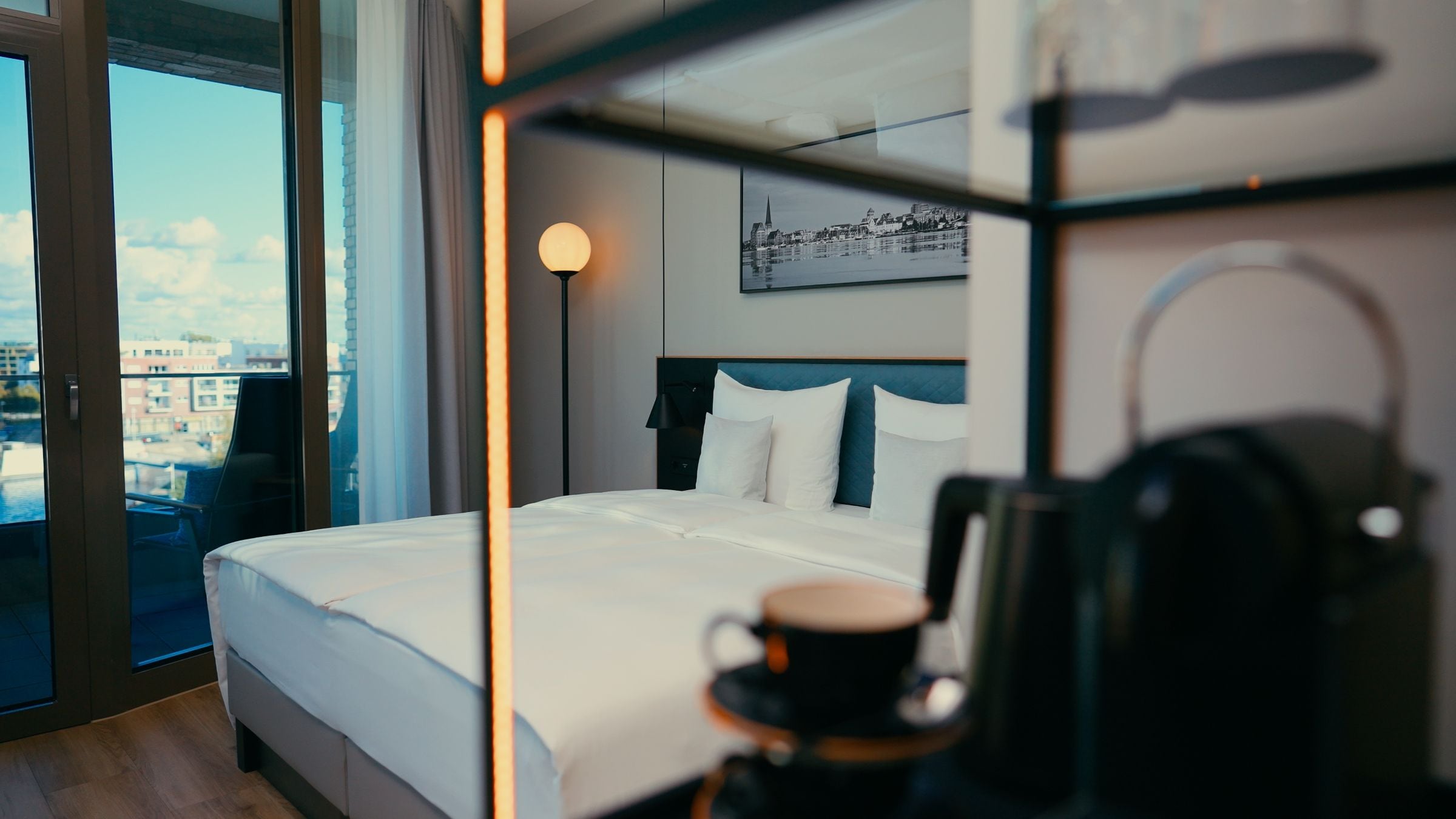 Une chambre d’hôtel avec un lit, une machine à café et une vue sur la ville par une grande fenêtre.
