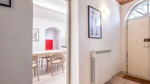 Un couloir avec une porte blanche, un radiateur et un tableau encadré accroché au mur.