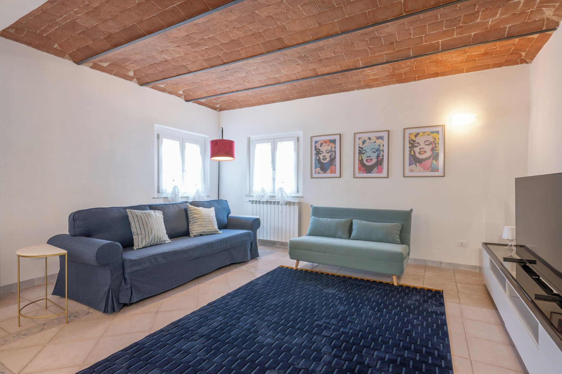 Een woonkamer met twee banken, een salontafel, een televisie en kunst aan de muur.