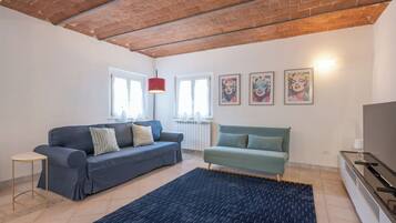 Een woonkamer met twee banken, een salontafel, een televisie en kunst aan de muur.