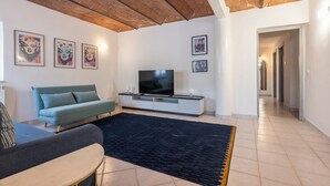Un salon avec un canapé, un téléviseur et des œuvres d’art accrochées au mur.