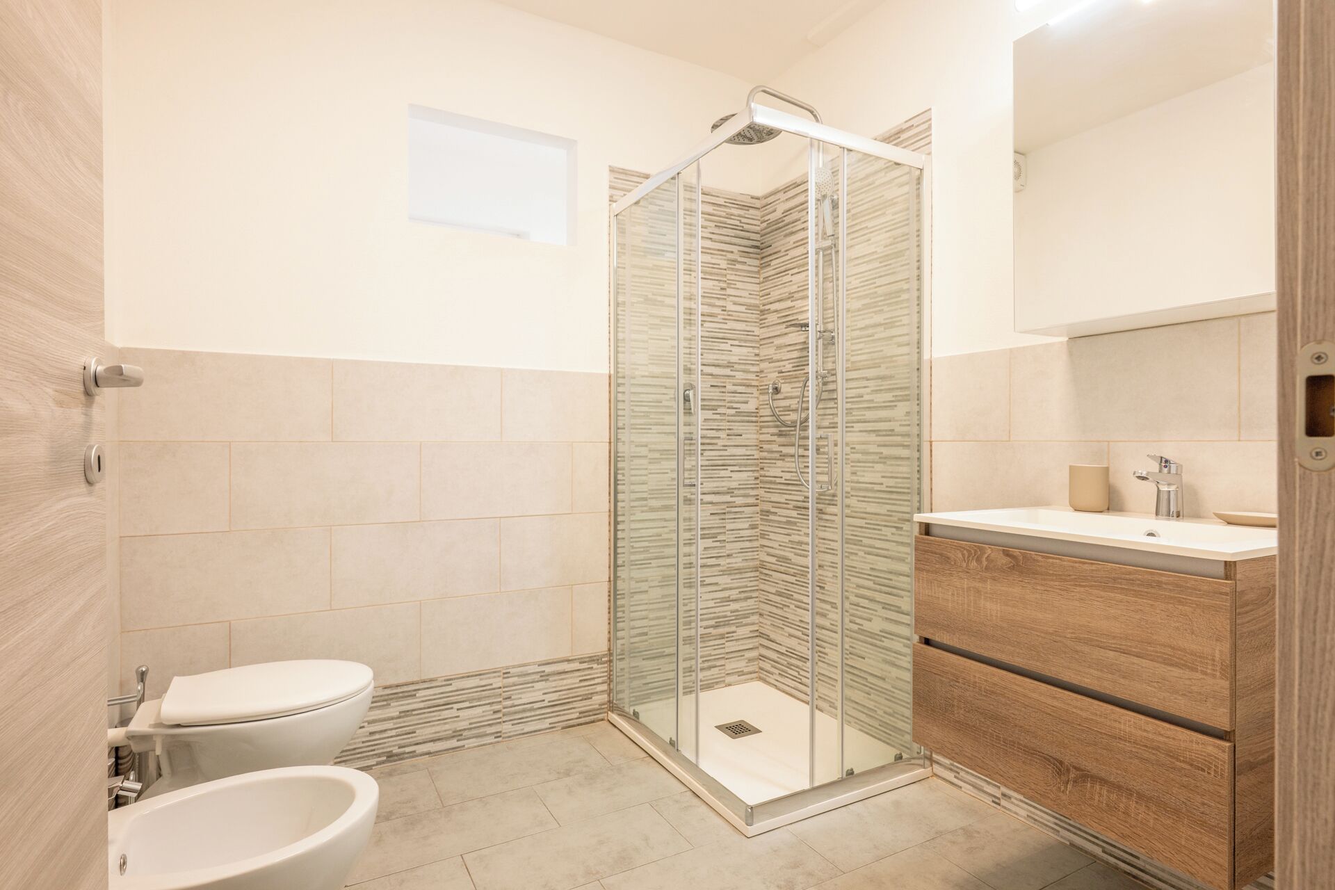 Une salle de bain moderne dotée d’une douche à parois de verre, de toilettes et d’un meuble-lavabo avec un miroir.