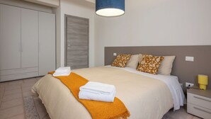 Une chambre à coucher avec un lit, une table de chevet, une lampe, une armoire et une porte.