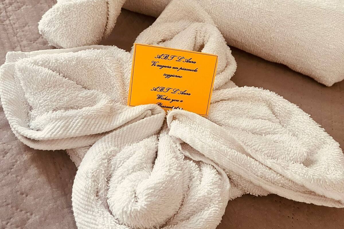 A neatly folded white towel with a yellow tag on a beige surface.