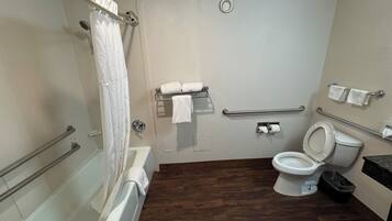 Un bagno dotato di vasca, servizi igienici e doccia. Sono presenti maniglie di sostegno e un corrimano.