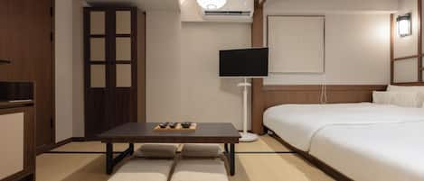 A hotel room with a bed, a TV, a desk with a chair, and a wardrobe.