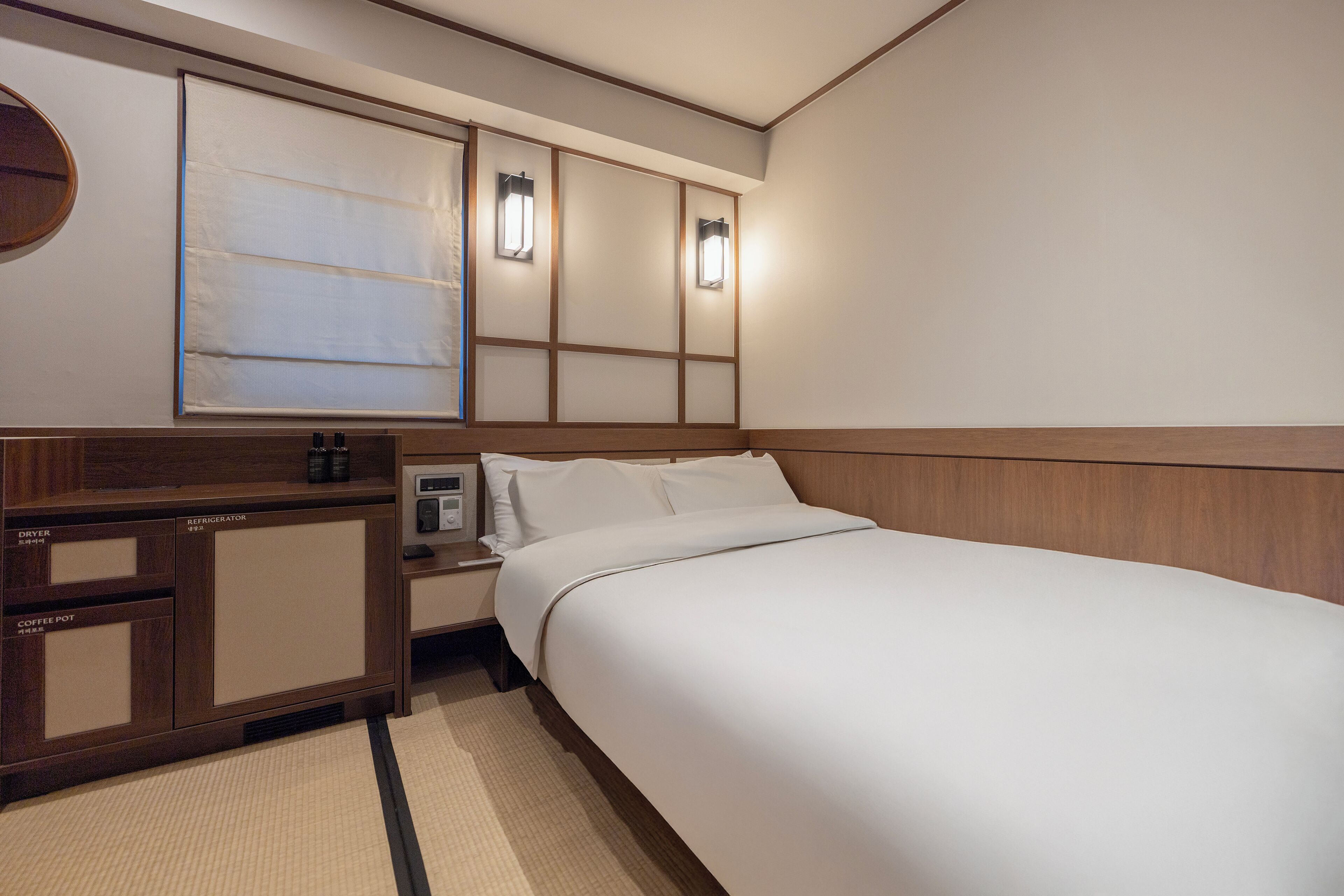 Una camera d'albergo con un letto, un comodino, una moka e un frigorifero.