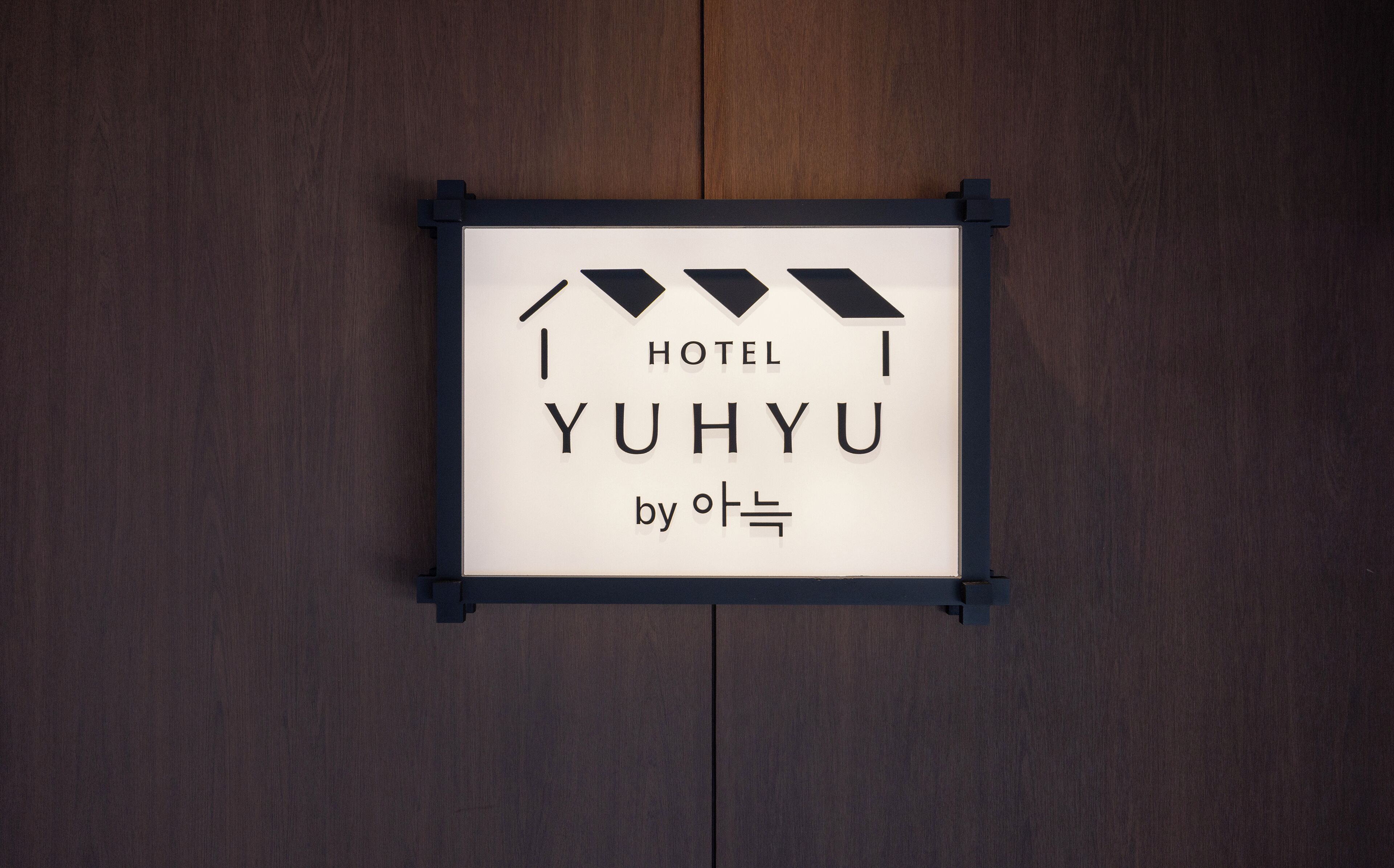 A sign with the text "HOTEL YUHYU by 아트" on a wooden background.