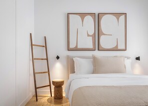 A bedroom with a wooden ladder, a round wooden stool, a bed with white bedding, and two wall-mounted light fixtures. - Kolonaki Athena Residence by Fineline  (Athens)