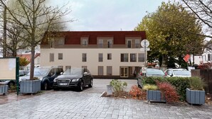Ein zweigeschossiges Gebäude mit rotem Ziegeldach, geparkten Autos und einem befestigten Zufahrtsweg.