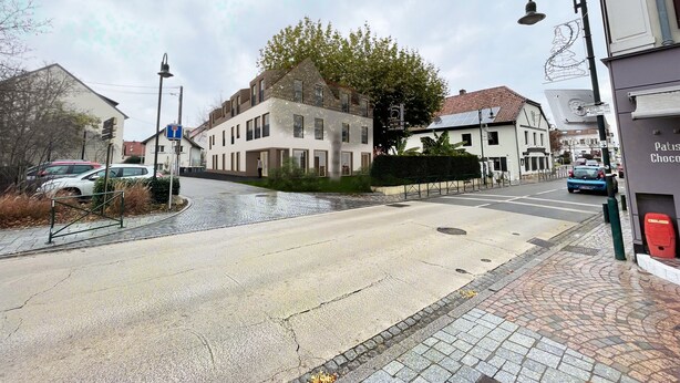 Straßenansicht mit einem zweigeschossigen Gebäude, einer Fußgängerzone und einem Schild für ein Geschäft.