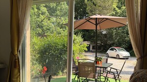 Una sala de estar moderna con una mesa de centro de vidrio, un sofá y vistas a un jardín y un coche aparcado a través de grandes puertas correderas de cristal.