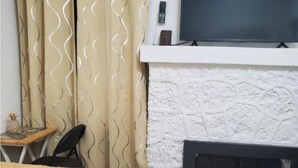 A room with a bed, a fireplace, a TV mounted above it, and curtains with a wavy pattern. - Affordable private bedroom with private bath with WiFi, AC in Miami B4 (Miami)