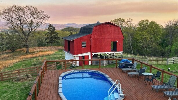 A red barn with a deck and a swimming pool.