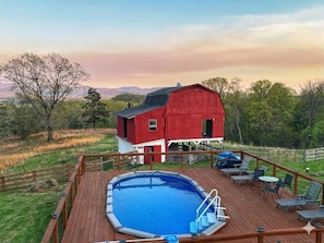 Une grange rouge avec une terrasse et une piscine.